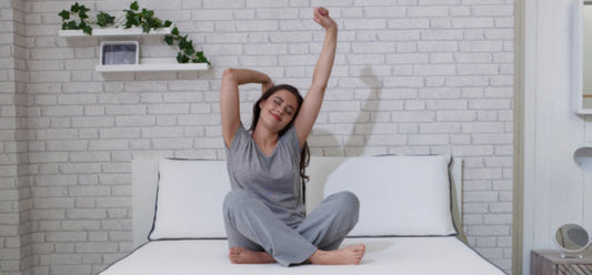 What to wear in bed - woman in pyjamas stretching on a memory foam mattress