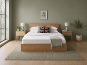 A bed with a white quilted mattress and matching white bedding, styled in a modern bedroom with a green wall, a Union Jack accent pillow, and light wood nightstands.